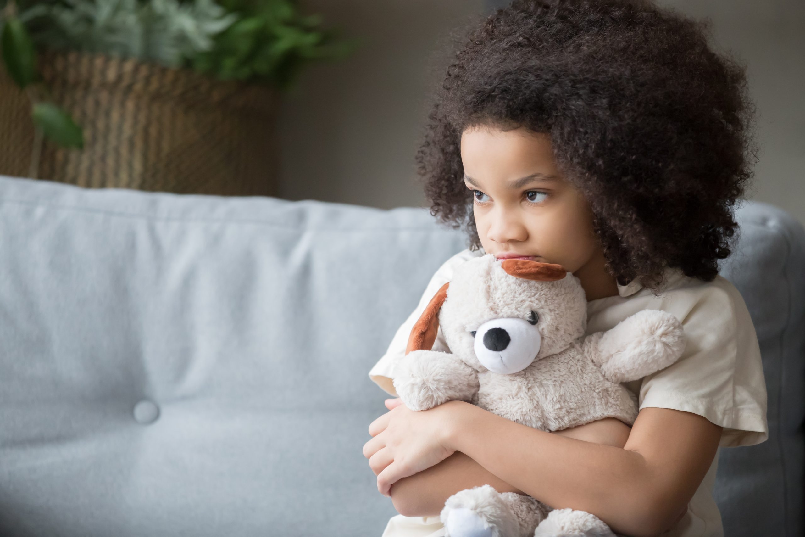 Young black girl hugs teddy bear toy
